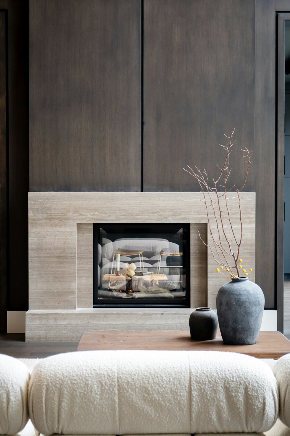 Travertine fireplace against dark walnut paneling in a staged living room
